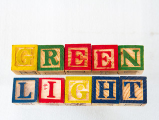 The term green light displayed visually on a white background using wooden toy blocks image with...