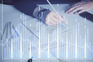 Double exposure of man's hands writing notes of stock market with forex chart.