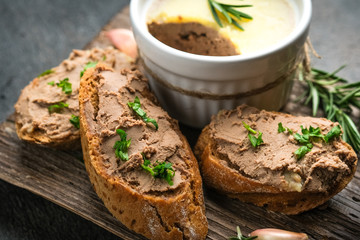 Fresh homemade chicken liver pate in ceramic bowl or ramekin and baguette slices with pate on the...