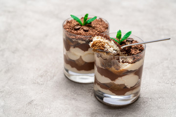 Classic tiramisu dessert in a glass cup on concrete background