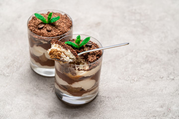 Classic tiramisu dessert in a glass cup on concrete background