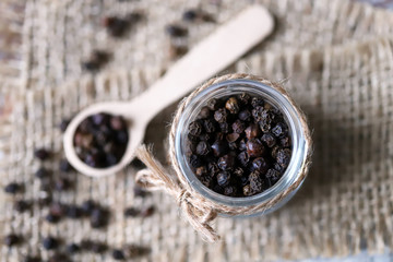Selective focus. Macro. Black pepper peas. Black pepper in a jar and in a wooden spoon.