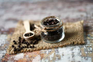 Selective focus. Macro. Black pepper peas. Black pepper in a jar and in a wooden spoon.