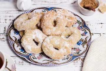 A dish with ring-shaped pastries over a white wooden table in horizontal
