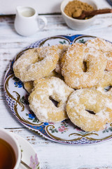 A dish with ring-shaped pastries over a white wooden table in vertical