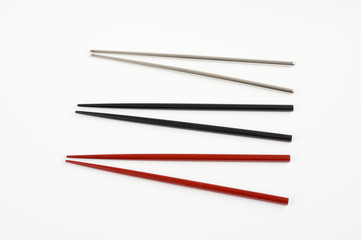 Wooden red , black and metal grey chopstick on white .