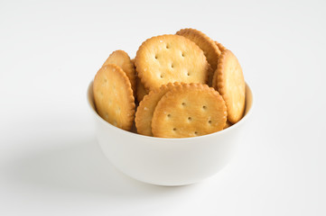 Crispy crackers in brown bowl on white background.