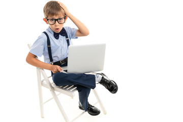little boy sitting on a chair with a laptop on his lap on a white background