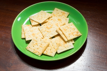 Crispy square crackers or cookies on green plate.