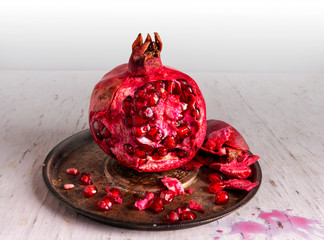 Large, ripe, red pomegranate on a silver plate. Appetizing red grains are scattered on the dishes.