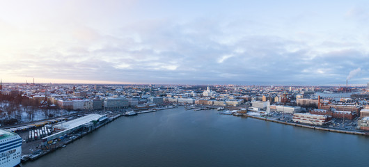 Fototapeta premium Aerial view Of Helsinki city from the sea. Sunset Evening Illuminations. Scenic winter view of the Old Port from the air. Finland. 