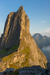 Fototapeta na wymiar Cliff wall bathed in evening sun. The mountain top Segla shaped as a sail, Senja, Norway.