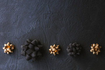 Gold and black bow for gift box on a black background. Christmas.