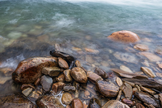 Closeup shot of twet rocks by the bridal veil waterfalls in rondane national park in norway. Wet stones and rainy weather with cascades and greenish water. Landscape and nature concept.