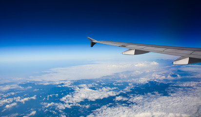 Fototapeta na wymiar Wing of airplane over white clouds