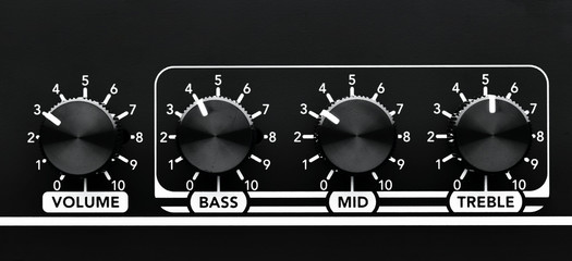 Close up detail of sound volume and equalizer control knobs of a black guitar amplifier