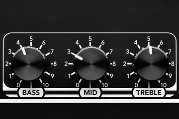 Close up detail of sound equalizer control knobs of a black guitar amplifier