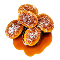Melted caramel candies and caramel sauce with a salt isolated on a white background. Macro