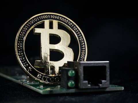 Shiny gold bitcoin virtual crypto currency coin laying on electronic circuit motherboard computer
