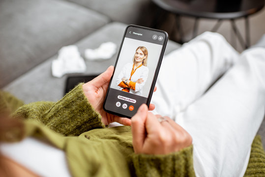Woman talking with a doctor online using smartphone, feeling bad at home, close-up on phone screen. Concept of telemedicine and patient counseling online