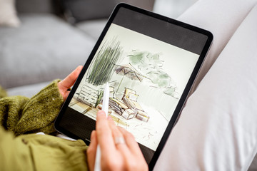 Artist or designer making landscape design, drawing on a digital tablet with pencil, close-up on a...