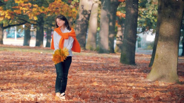 Young woman enjoying autumn leaf fall in park