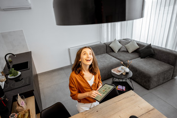 Young woman controlling home light with a digital tablet in the living room. Concept of a smart...
