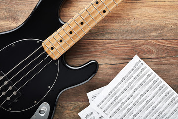 Obraz na płótnie Canvas Black bass guitar with headphones and sheet music on wooden table