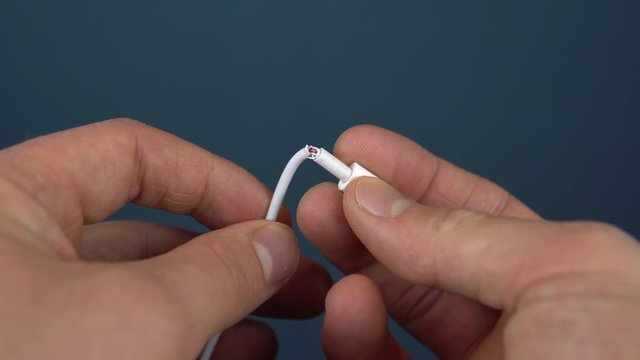 Torn phone charger cable closeup. A man holds a torn wire in his hands. Wire wear