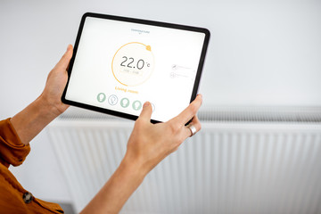 Controlling radiator heating temperature with a tablet, close-up with radiator on the background....