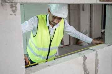 Fototapeta premium Engineer checking defect in construction site measure dimention of window on wall panel