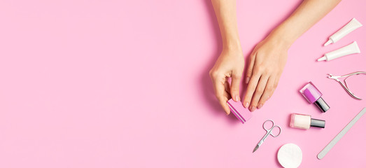 Obraz na płótnie Canvas Stylish beautiful gentle manicure. Hands of young woman with nail file, manicure tools on pink background top view flat lay. Natural nails gel polish self-care beauty and fashion. Nail care salon spa