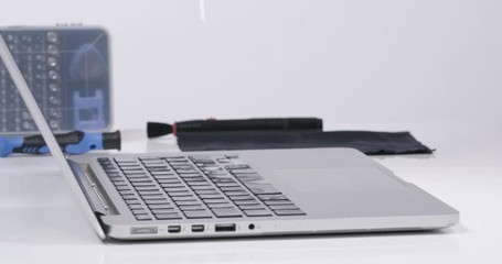 Service worker cleaning laptop keyboard buttons with compressed air in white walled lab in 4k