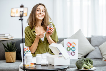 Young woman recording on a smart phone her vlog about healthy eating and nutritional supplements....
