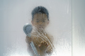 Asian boy playing with soap and water from shower head