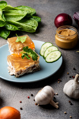 Piece of homemade jelly with meat on the plate. Aspic poultry and beef, traditional Russian and Ukrainian dish with mustard, spices and different ingredients. Holodets