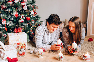 happy couple lies near christmas tree with candles