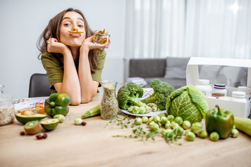 Portrait of a young cheerful woman with lots of healthy green food on the table. Concept of...