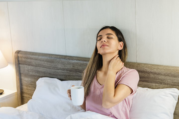 Woman sitting on bed drinking coffee smiling