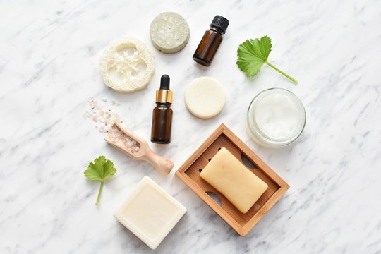 Zero waste cosmetic, natural self care products, soaps, shampoo bars, essential oils, flat lay with copy space on marble background.