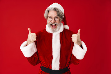 Fototapeta na wymiar Image of adult Santa Claus man in red costume gesturing thumbs up
