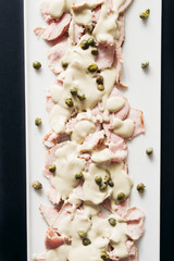 Vitello tonnato on a is a Italian dish of cold, sliced veal covered with a creamy, mayonnaise-like sauce that has been flavored with tuna.[object Object]