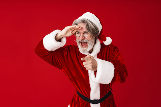Image of gray-haired Santa Claus old man in red costume pointing finger