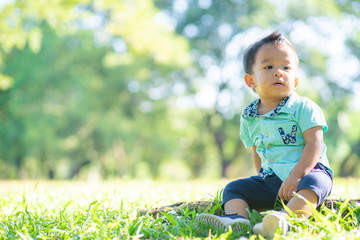 Funny. baby boy plying on green grass in city park