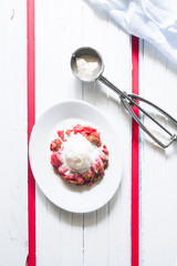 Crunchy strawberries crumble, top view, served with vanilla ice cream, on an oval serving dish, , white background