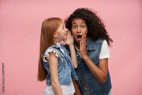 Indoor Photo Of Attractive Young Girls Wearing Family Look While Posing Over Pink Background Keeping Hands Near Their Faces While Sharing With Each Other Surprising News Wall Mural Timtimphoto Indoor Photo Of Attractive Young Girls Wearing Family Look While Posing Over Pink Background Keeping Hands Near Their Faces While Sharing With Each Other Surprising News Wall Mural Timtimphoto