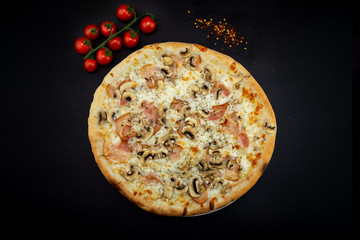 Isolated round pizza on black background with tomatoes