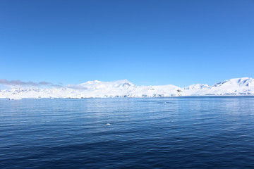 Fototapeta na wymiar Snow-capped mountains on an island along the coasts of the Antarctic Peninsula, Palmer Archipelago, Antarctica