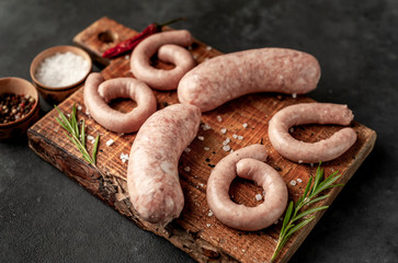 Raw grilled sausages with spices and rosemary, on a stone table, cooking concept