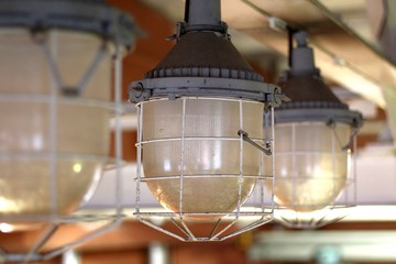 Fototapeta na wymiar Old industrial pendant lamp. Glass shade in a steel mesh.